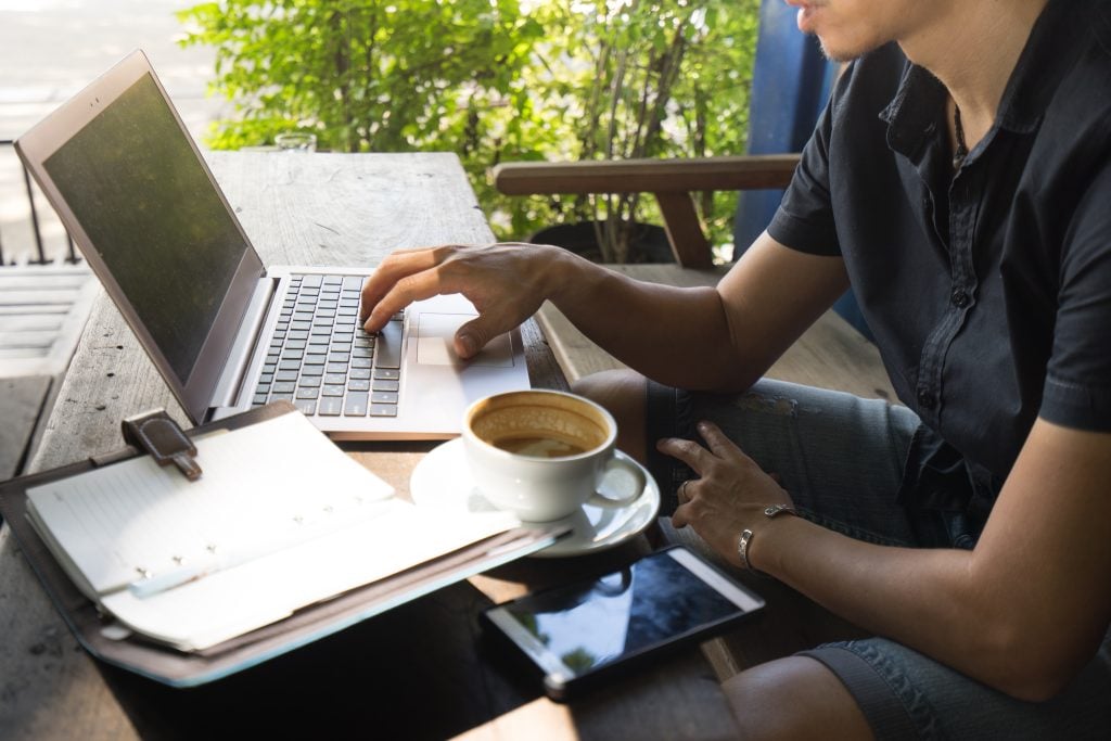 Smart asian man digital nomad sit and working on freelance project using portable computer ,smartphone and making notes in the paper note.