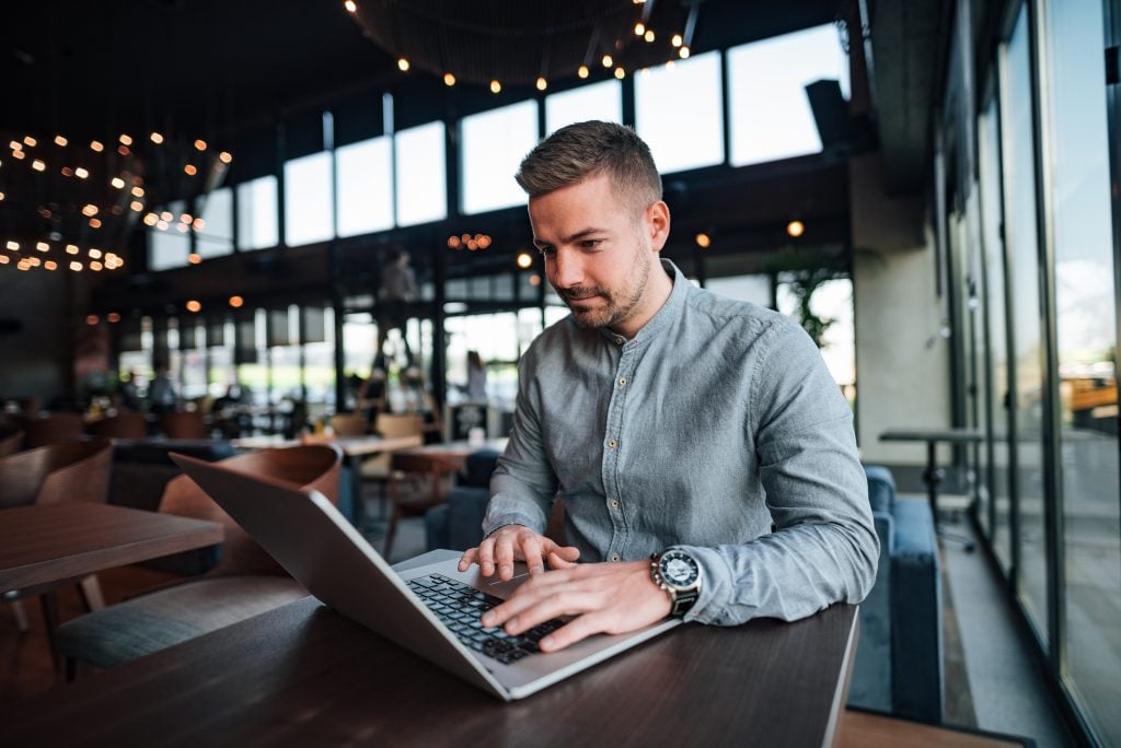 Young freelancer working on laptop in cafe.