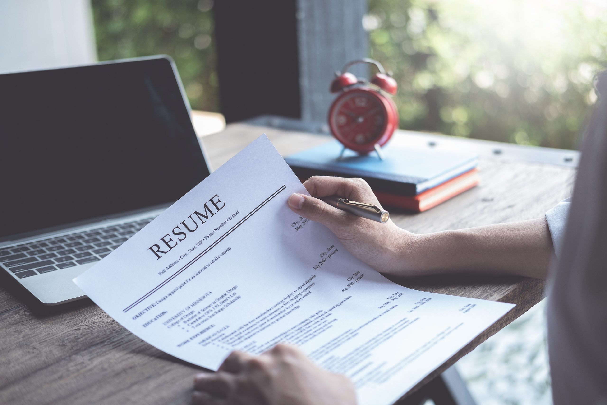 Business man review his resume application on desk, laptop computer