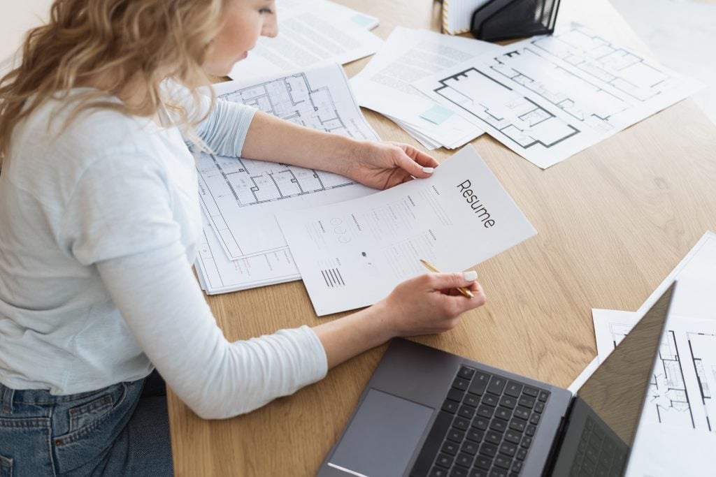 Businesswoman sitting in office, checking cv document