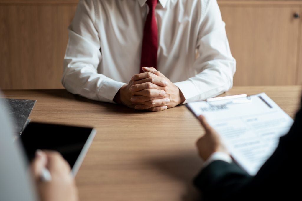 HR manager woman reading resume and writing data on tablet during job interview with male candidate