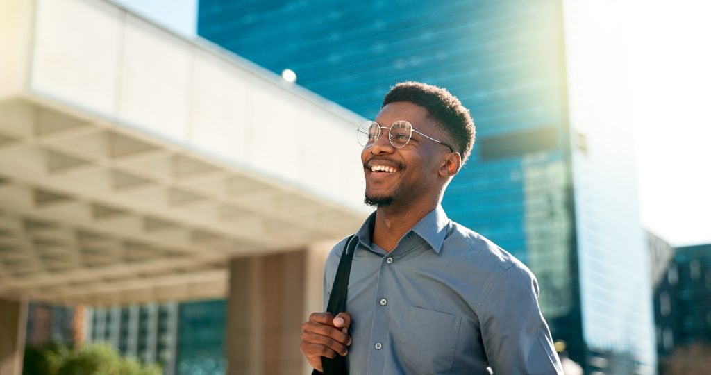 Business, happy and walking black man on city journey, commute trip and realtor smile on way to office building. Happiness, career expert and African real estate agent on morning travel in Nigeria