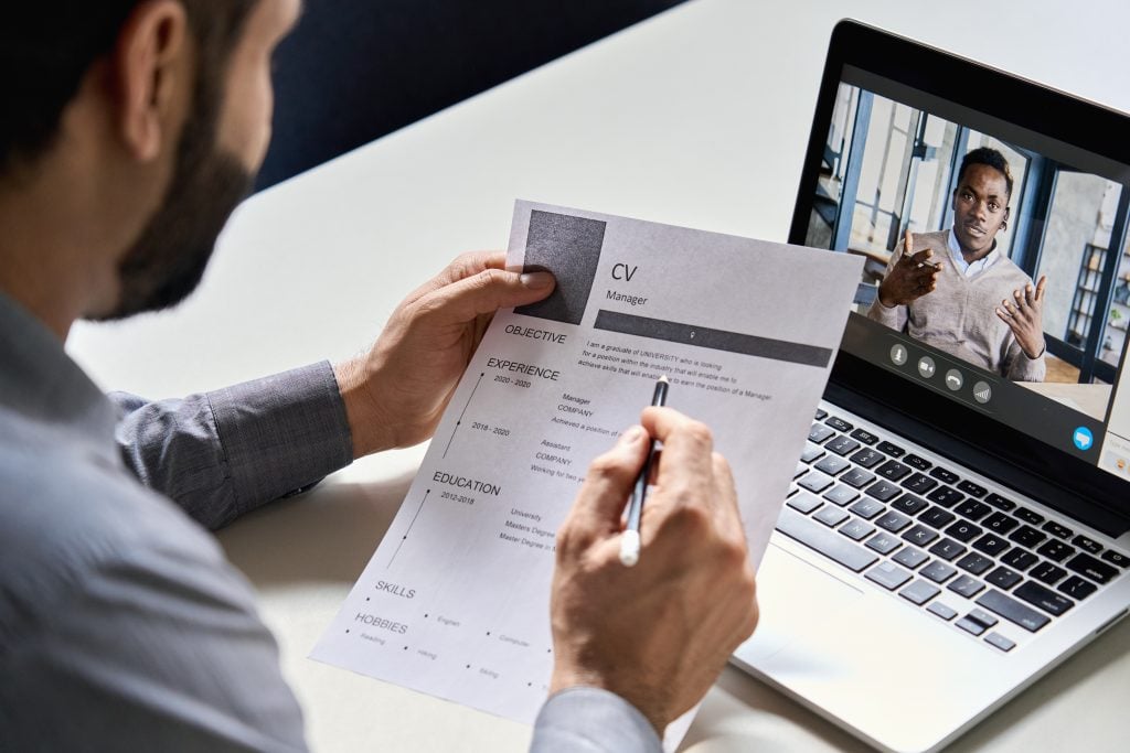 Indian employer reading cv during virtual job interview with african candidate.