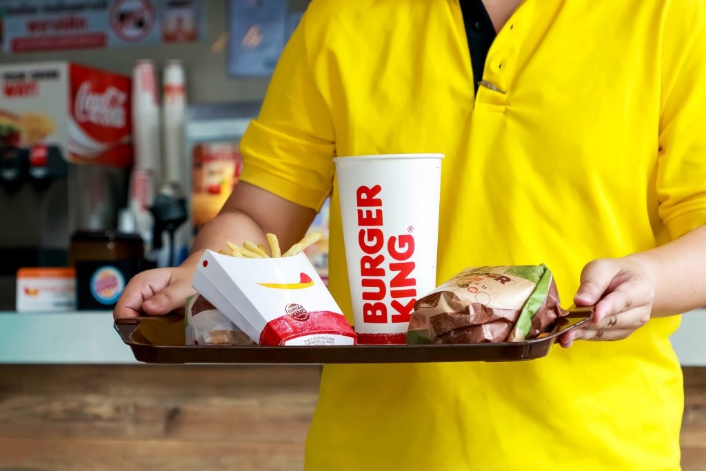 Man holding tray of Burger king set has whopper hamburger french fries and paper glass of cola drink.