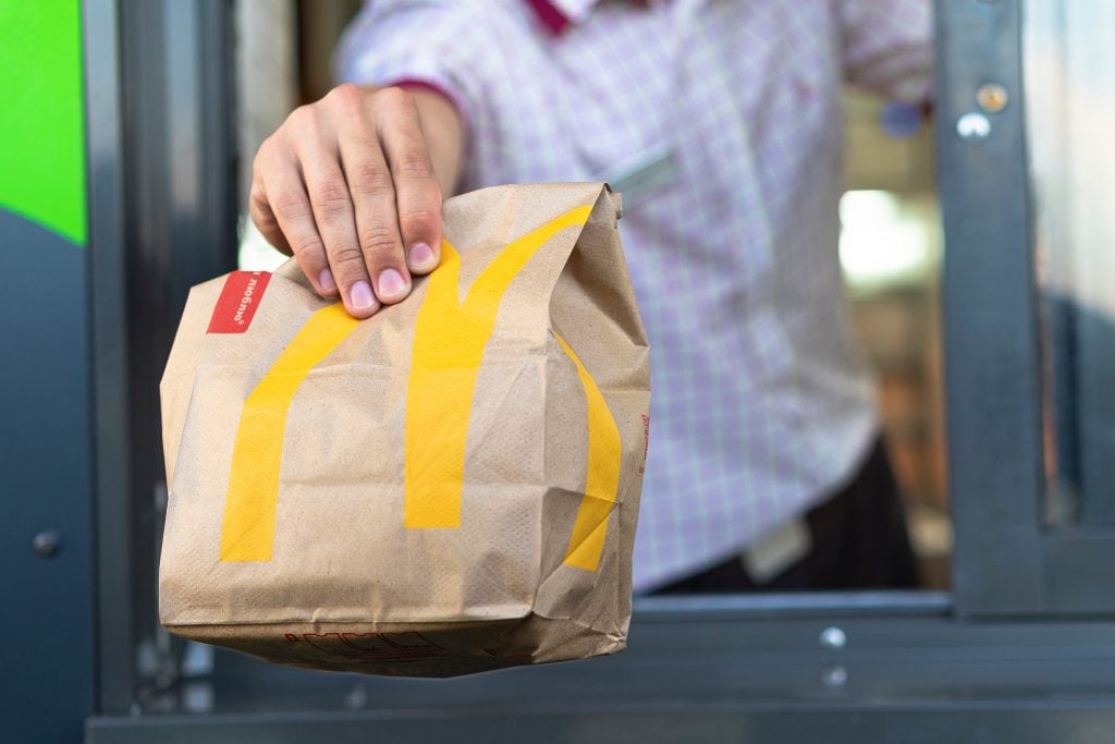 McDonald’s worker holding bag of fast food.