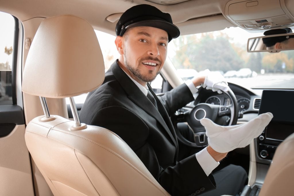 Handsome chauffeur driving luxury car